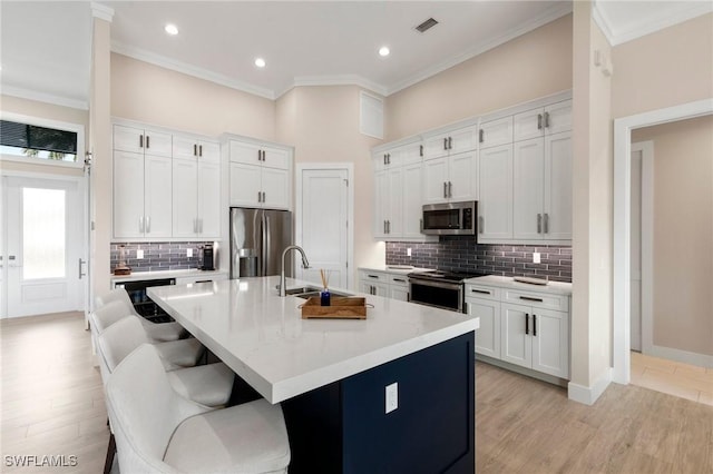 kitchen with white cabinets, stainless steel appliances, and an island with sink