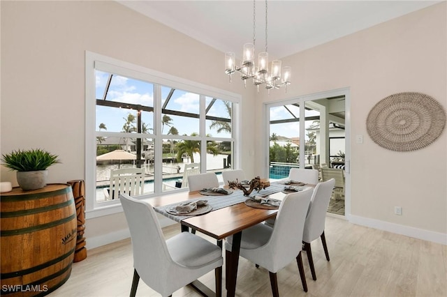 dining area with a water view, a chandelier, and light hardwood / wood-style flooring