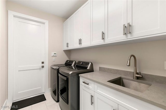 clothes washing area with sink, light tile patterned floors, cabinets, and independent washer and dryer