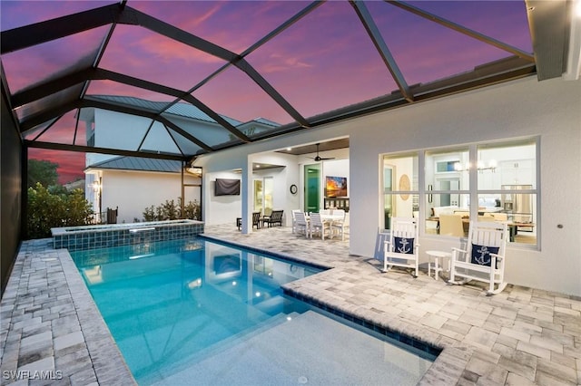 pool at dusk featuring a patio area, a lanai, and ceiling fan