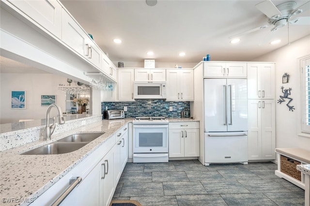 kitchen featuring white cabinetry, sink, decorative backsplash, light stone countertops, and white appliances