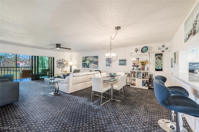 carpeted dining room with ceiling fan with notable chandelier and a textured ceiling