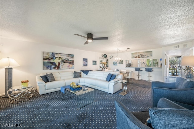 living room with ceiling fan, carpet floors, and a textured ceiling