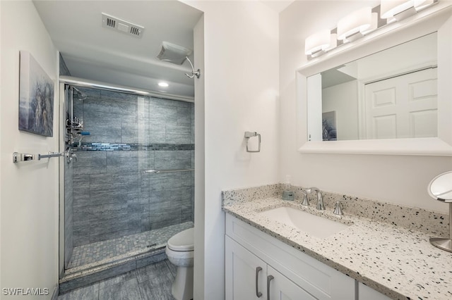 bathroom featuring vanity, hardwood / wood-style flooring, a shower with shower door, and toilet