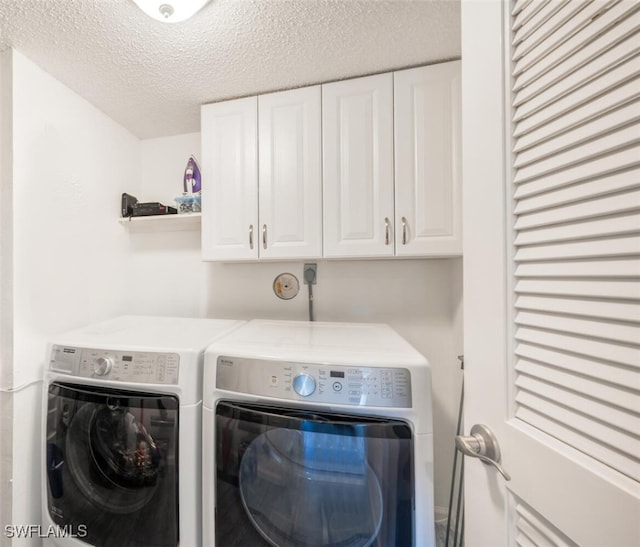 laundry area featuring cabinets, washing machine and clothes dryer, and a textured ceiling