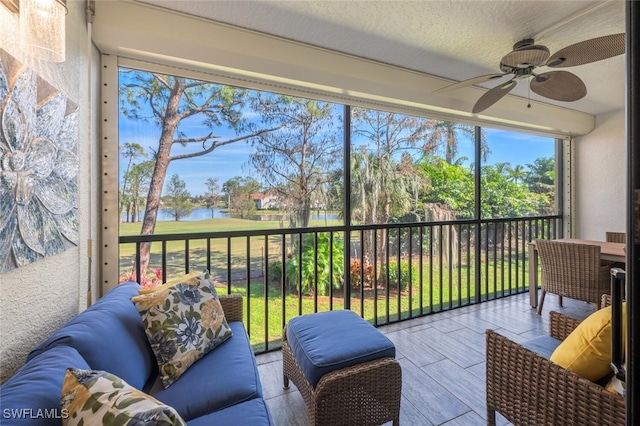 sunroom featuring a water view and ceiling fan