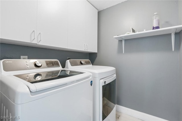 washroom featuring a textured ceiling, cabinets, and washing machine and clothes dryer