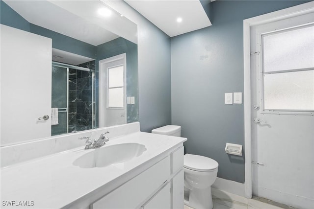 bathroom with vanity, a shower with door, and toilet