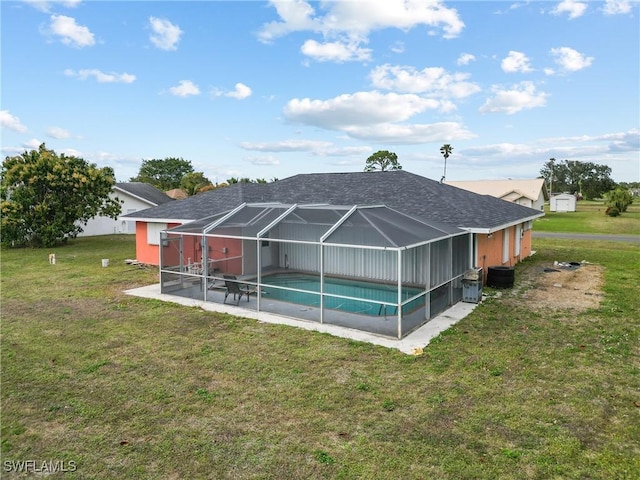 back of house with a lanai, a patio, and a lawn