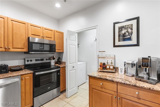 kitchen featuring light stone counters, appliances with stainless steel finishes, washer / dryer, and light tile patterned floors