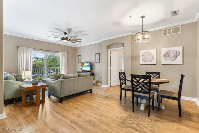 living area with ceiling fan, light wood-style floors, ornamental molding, baseboards, and arched walkways