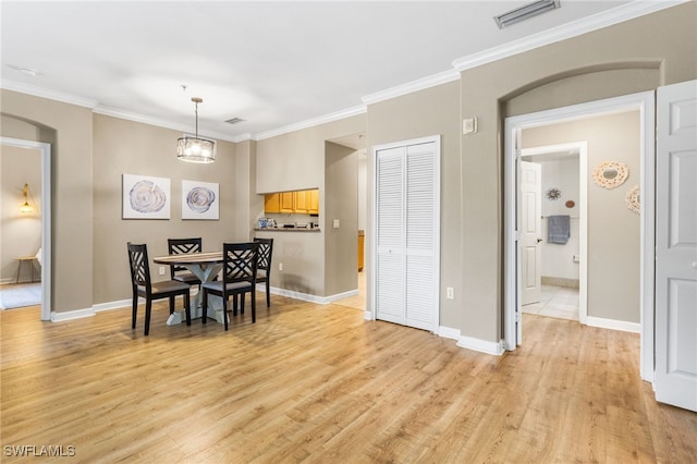 dining space with crown molding and light hardwood / wood-style floors