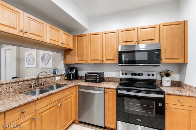 kitchen featuring light stone countertops, appliances with stainless steel finishes, sink, and light tile patterned floors