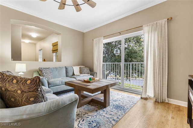 living room with crown molding, wood finished floors, baseboards, arched walkways, and a ceiling fan