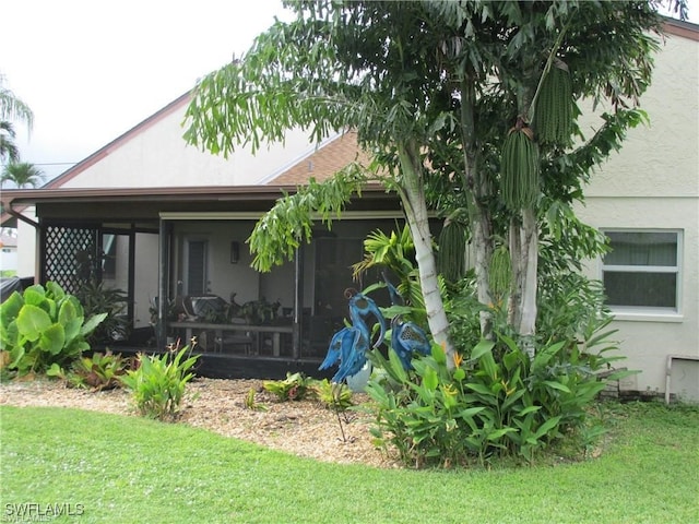 view of property exterior featuring a sunroom and a lawn