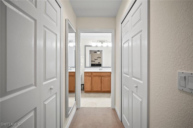 corridor with sink and light carpet