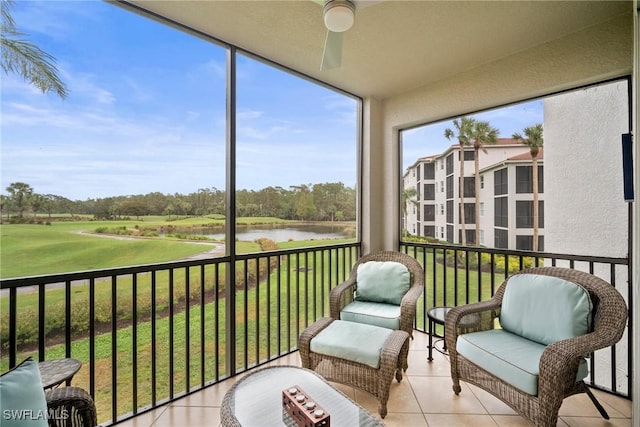 sunroom with ceiling fan and a water view