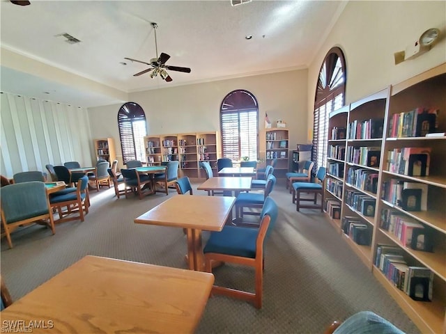 carpeted dining room featuring visible vents, ornamental molding, and a ceiling fan