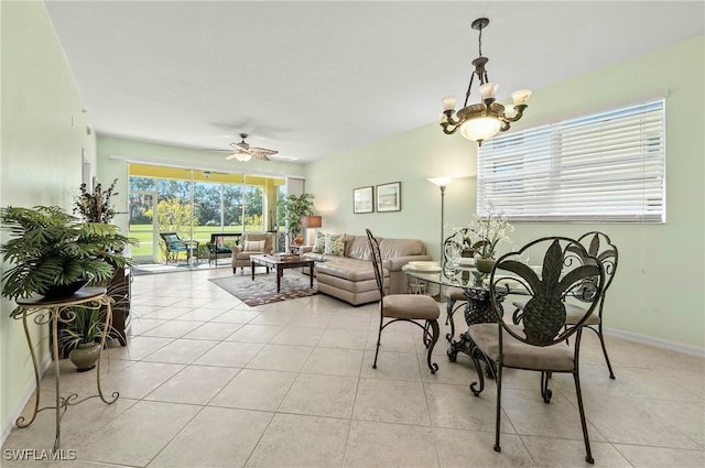 dining space with light tile patterned floors, ceiling fan with notable chandelier, and baseboards