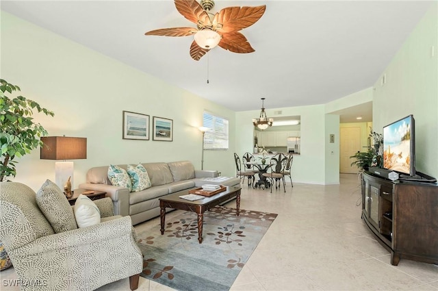 living area with light tile patterned floors, ceiling fan with notable chandelier, and baseboards