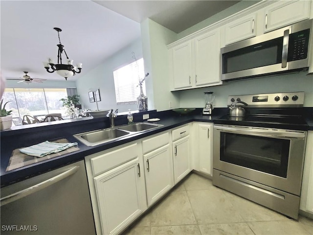 kitchen with dark countertops, a notable chandelier, white cabinets, stainless steel appliances, and a sink