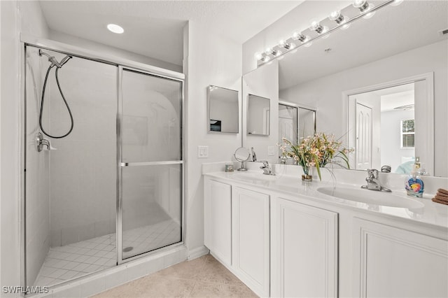 bathroom featuring a sink, a stall shower, double vanity, and tile patterned flooring