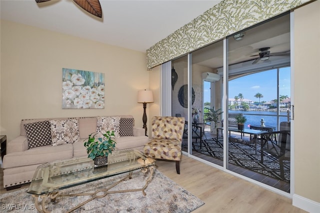 living room featuring hardwood / wood-style floors, a water view, and ceiling fan