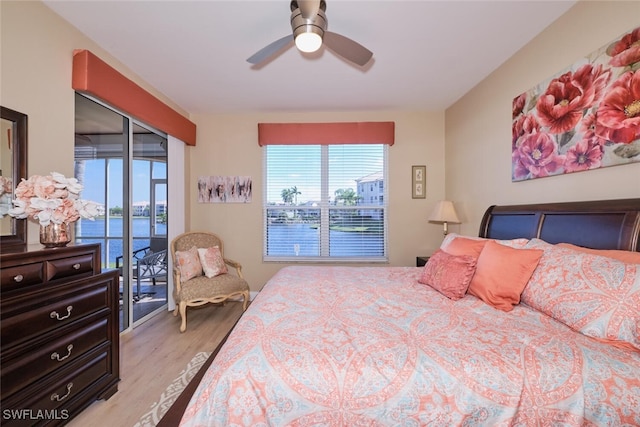 bedroom featuring ceiling fan, access to exterior, multiple windows, and a water view