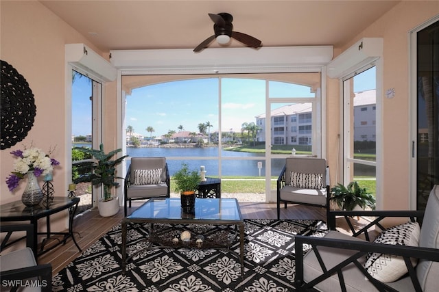 sunroom / solarium featuring ceiling fan and a water view