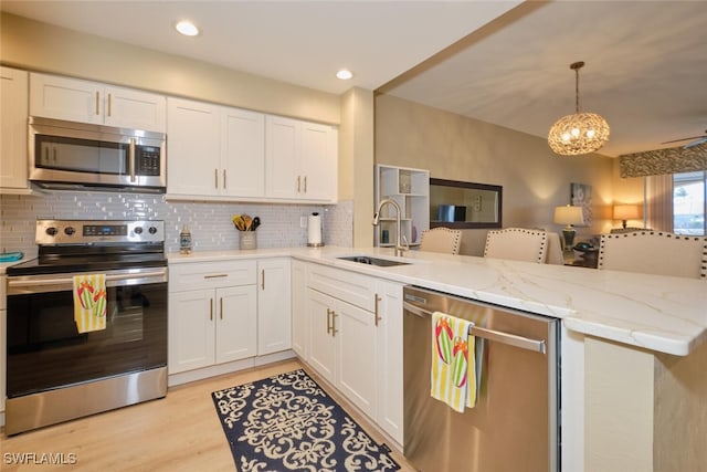 kitchen featuring kitchen peninsula, sink, white cabinets, and appliances with stainless steel finishes