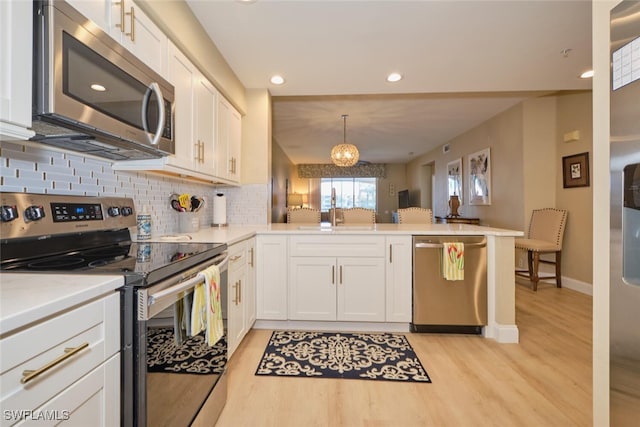 kitchen featuring stainless steel appliances, white cabinetry, kitchen peninsula, and pendant lighting