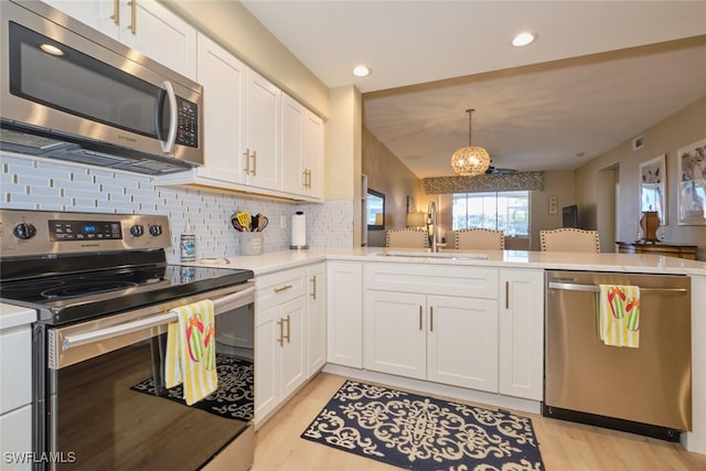 kitchen with white cabinetry, decorative backsplash, sink, kitchen peninsula, and stainless steel appliances