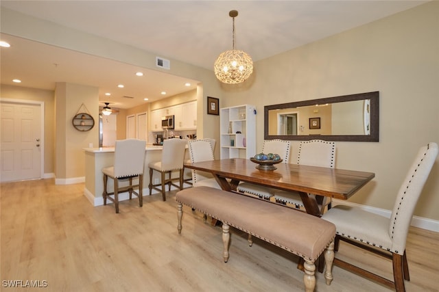 dining space with light hardwood / wood-style floors and ceiling fan with notable chandelier