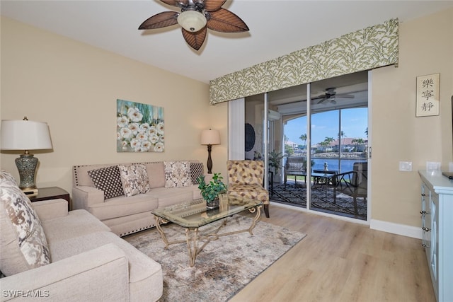 living room with light wood-type flooring, ceiling fan, and a water view