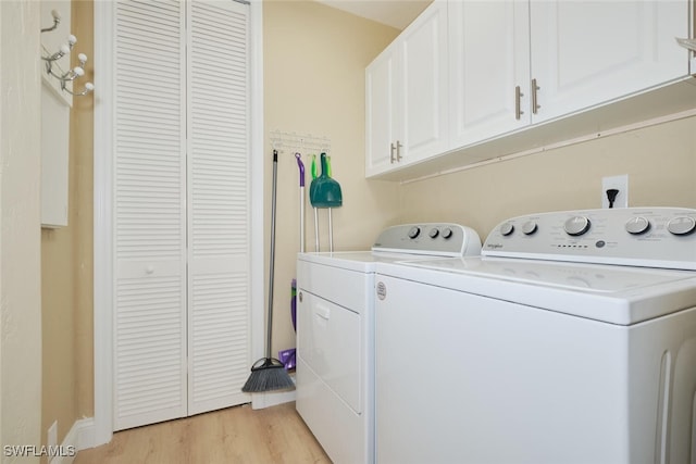 clothes washing area with cabinets, light hardwood / wood-style flooring, and separate washer and dryer