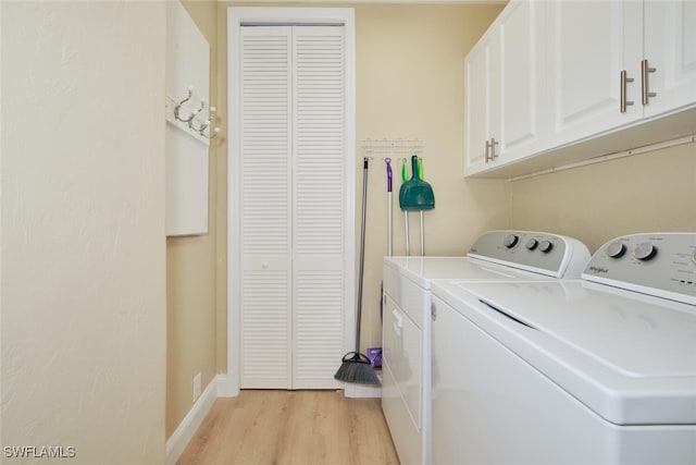 laundry area with light hardwood / wood-style flooring, cabinets, and washer and dryer