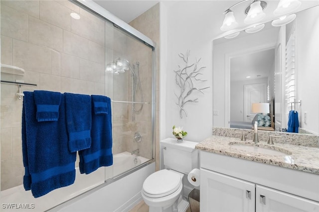 full bathroom with vanity, bath / shower combo with glass door, and toilet