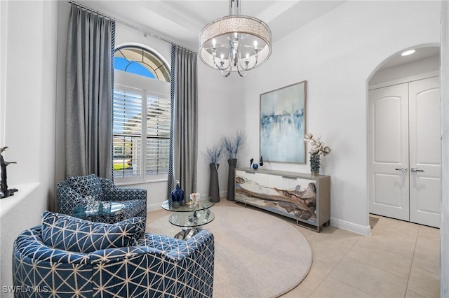 sitting room featuring tile patterned flooring, ornamental molding, and a chandelier