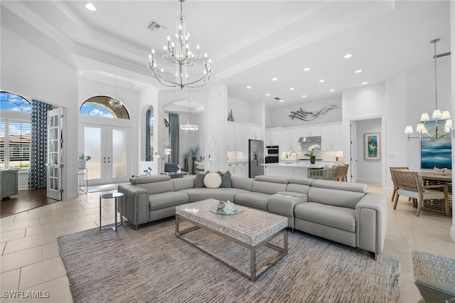 tiled living room featuring french doors, sink, a chandelier, a tray ceiling, and a high ceiling