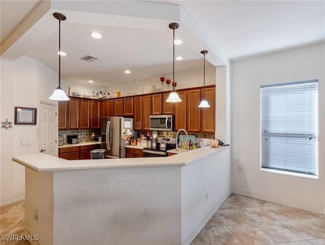 kitchen featuring appliances with stainless steel finishes, decorative light fixtures, and kitchen peninsula