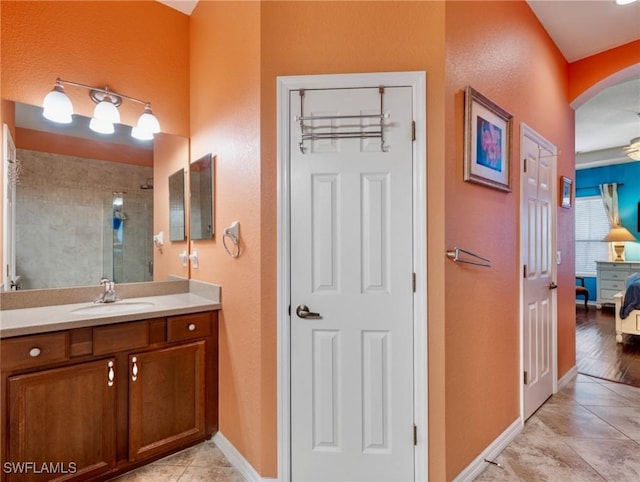 bathroom with tile patterned flooring, vanity, and a tile shower