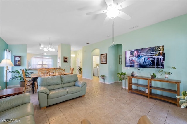 tiled living room with ceiling fan with notable chandelier