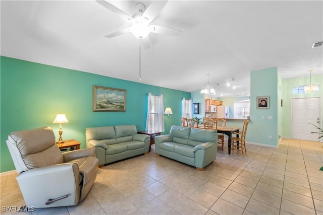 tiled living room with ceiling fan with notable chandelier and vaulted ceiling