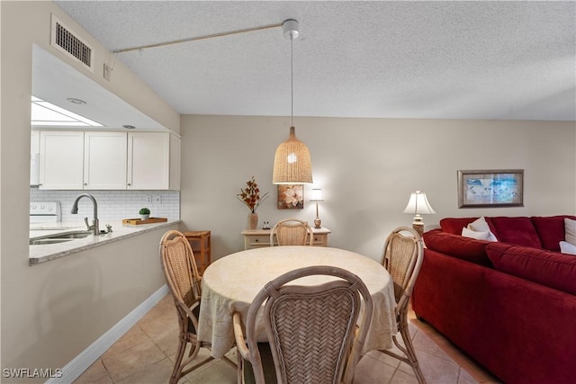 tiled dining room featuring sink and a textured ceiling