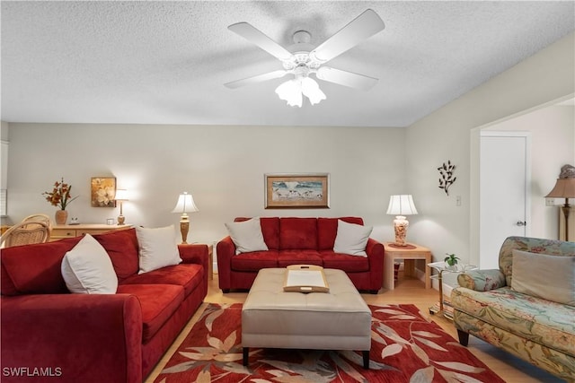 living room with ceiling fan, a textured ceiling, and light hardwood / wood-style flooring