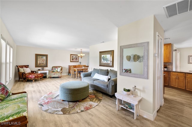 living room with light hardwood / wood-style floors and an inviting chandelier