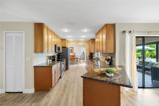 kitchen with sink, stainless steel appliances, dark stone counters, and tasteful backsplash