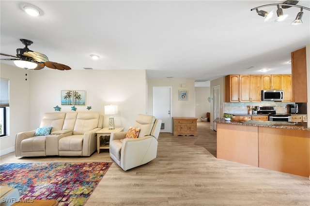 kitchen with stainless steel appliances, ceiling fan, light hardwood / wood-style floors, and decorative backsplash