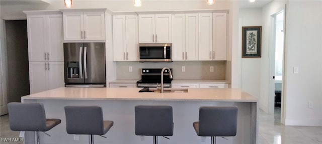 kitchen featuring white cabinetry, stainless steel appliances, sink, and an island with sink