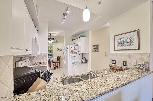 kitchen with white appliances, track lighting, white cabinetry, sink, and hanging light fixtures